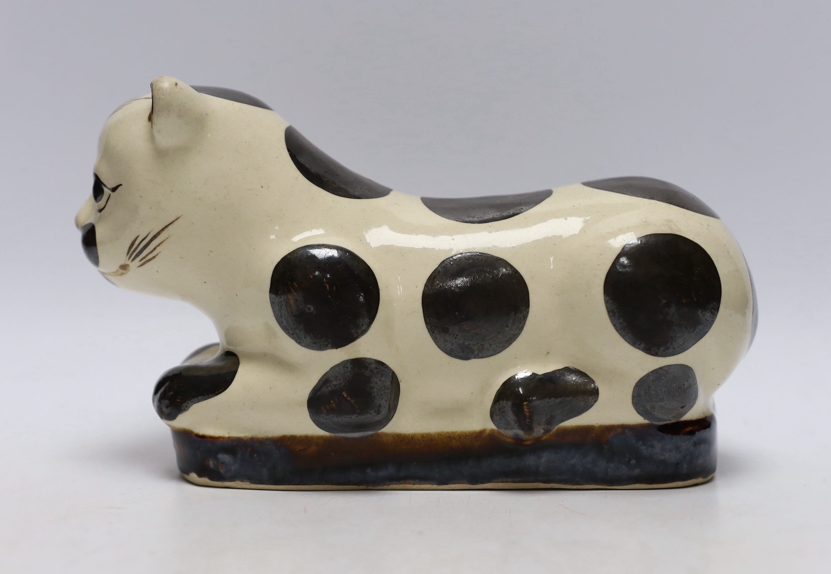 A Chinese glazed earthenware cizhou style pillow headrest in the form of a black and white cat, 22cm